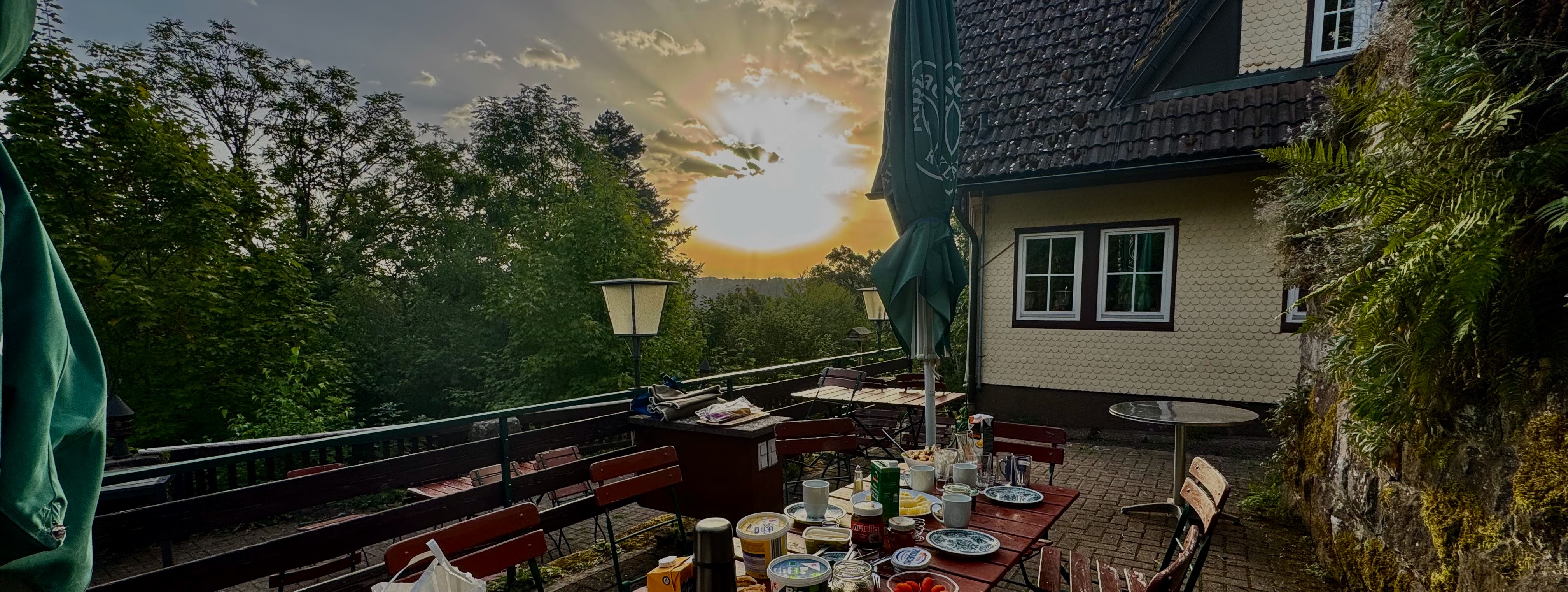 Gedeckter Frühstückstisch auf der Burgstüble-Terrasse, Sonne bricht überm Schwarzwald durch die Wolken