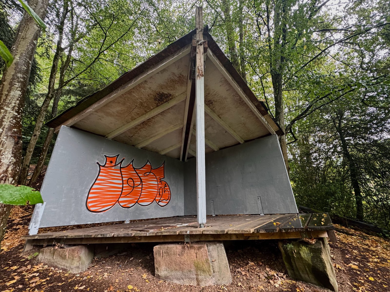 Die frisch grundierte Holzmuschel im Park der Zeiten – graue Wände, nur das orangene Graffiti steht noch
